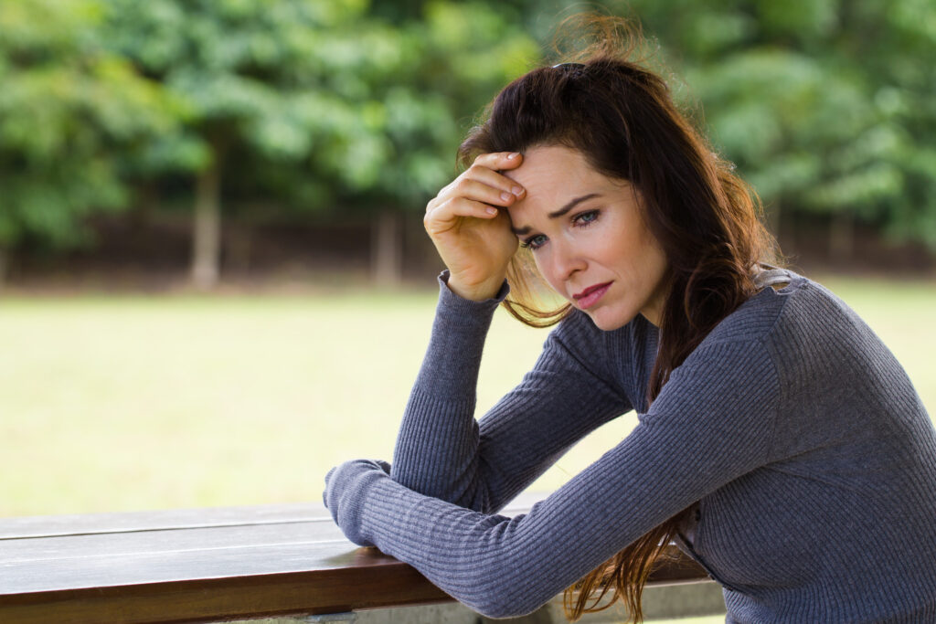 sad and worried woman sitting outdoors